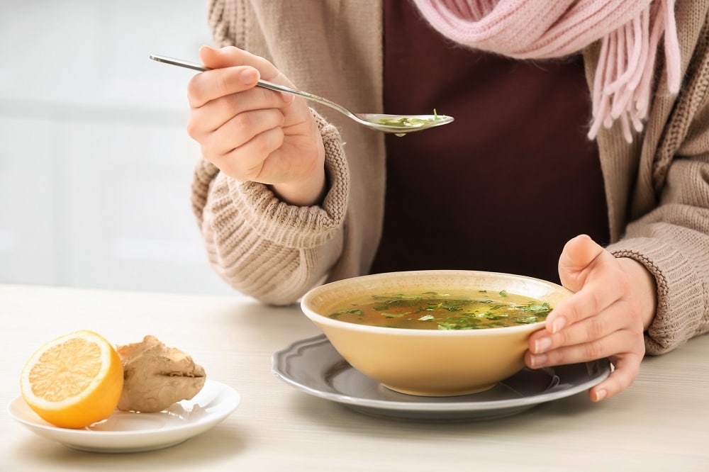 Sick,Young,Woman,Eating,Broth,To,Cure,Cold,At,Table