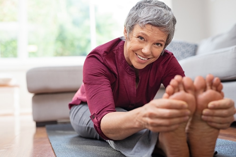 Closeup,Of,Senior,Woman,Stretching,To,Touch,Toes,While,Sitting