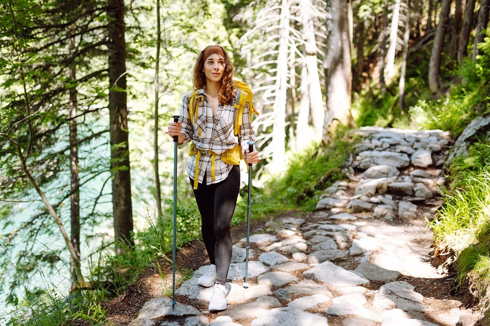 Young,Woman,With,Backpacks,And,Walking,Sticks,Hiking,In,Nature.
