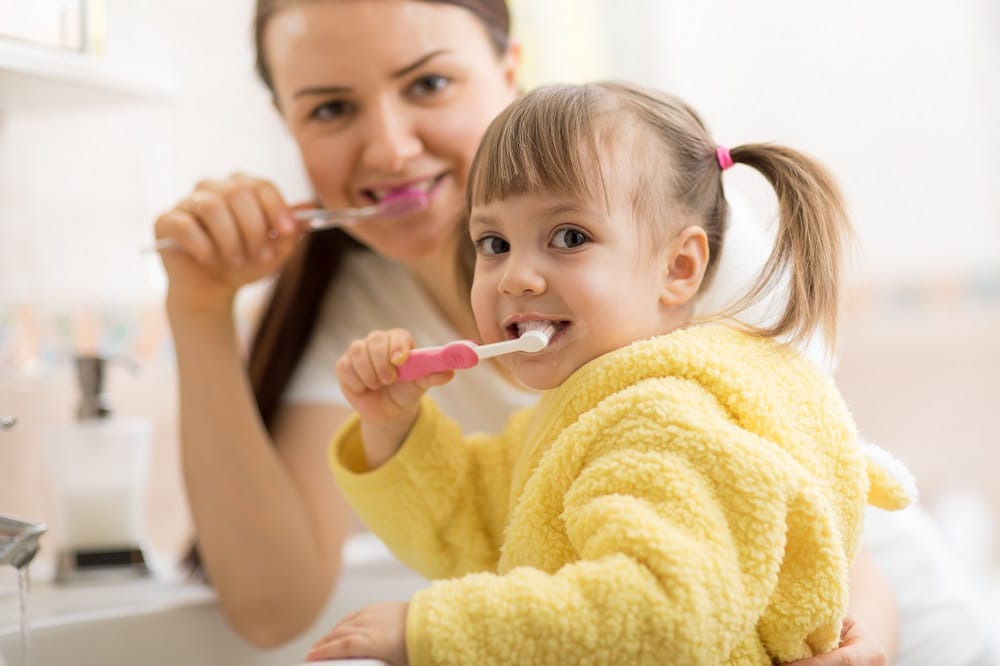 Smiling,Child,Girl,With,Her,Mom,Brushing,And,Clean,Teeth