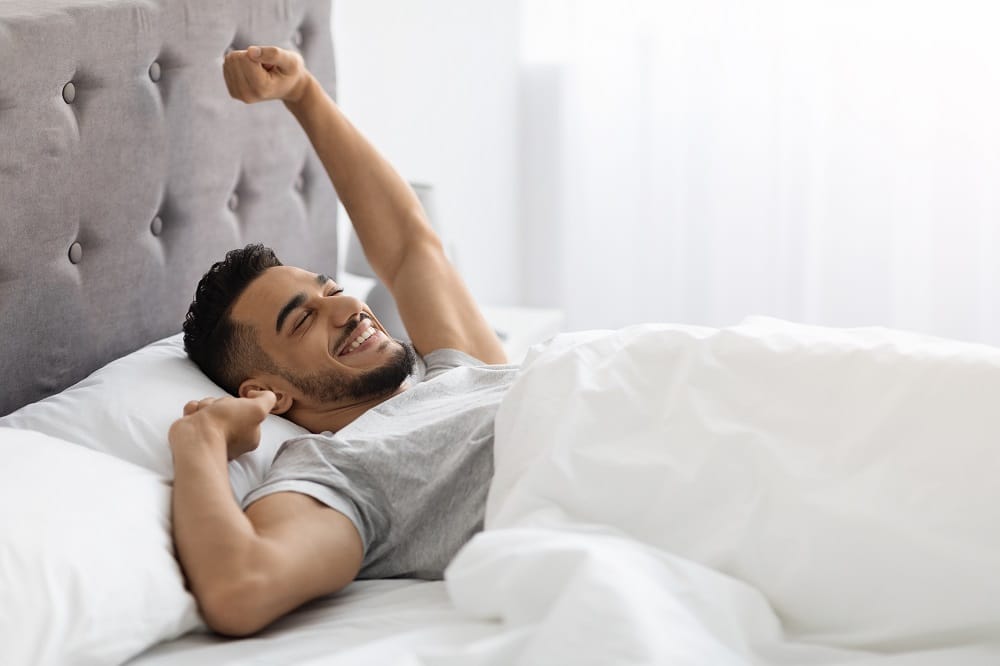Lazy,Morning.,Happy,Pleased,Middle,Eastern,Man,Stretching,In,Bed