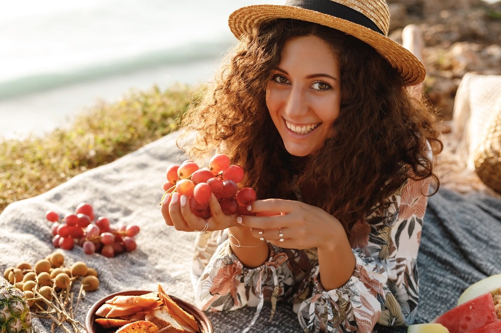 Smiling,Curly,Hair,Woman,In,Straw,Hat,Having,Picnic,By