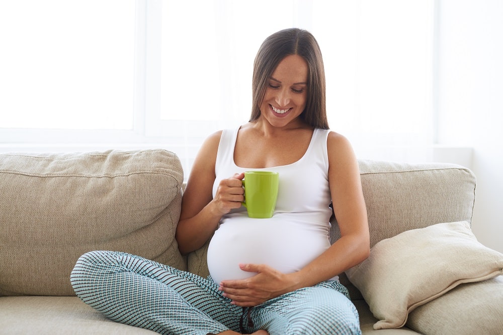 Closeup,Of,Pregnant,Happy,Woman,Sitting,On,Sofa,And,Drinking